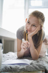 Girl learning at home, writing in exercise book - DKOF00005