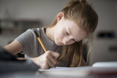 Girl learning at home, writing in exercise book - DKOF00007