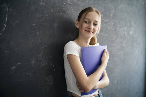 Girl with exersice books in front of black wall - DKOF00019