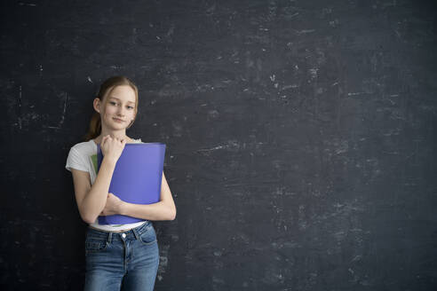 Girl with exersice books in front of black wall - DKOF00020