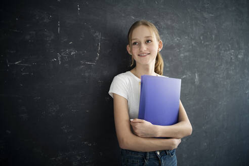 Girl with exersice books in front of black wall - DKOF00023