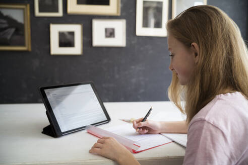 Blond girl learning and using tablet at home - DKOF00035