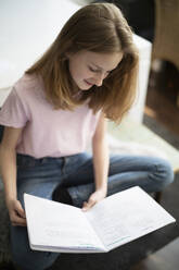 Mädchen liest in einem Übungsbuch zu Hause - DKOF00038