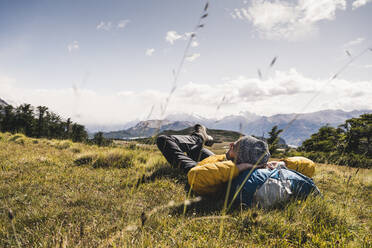 Mann mit Händen hinter dem Kopf, der auf einem Berg in Patagonien, Argentinien, Südamerika, ruht - UUF20813