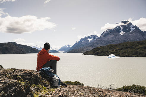 Mann schaut auf einen Fluss, während er im Torres Del Paine National Park sitzt, Patagonien, Chile, Südamerika - UUF20825