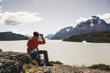 Mann betrachtet den Grey Glacier mit einem Fernglas im Torres Del Paine National Park, Patagonien, Chile, Südamerika - UUF20829