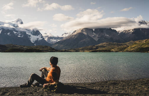 Mann sitzt und bewundert die Aussicht auf den Pehoe-See im Nationalpark Torres Del Paine, Chile Patagonien, Südamerika - UUF20840