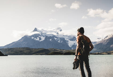 Mann mit Schuhen bewundert den Blick auf den Pehoe-See im Torres Del Paine National Park, Chile Patagonien, Südamerika, lizenzfreies Stockfoto