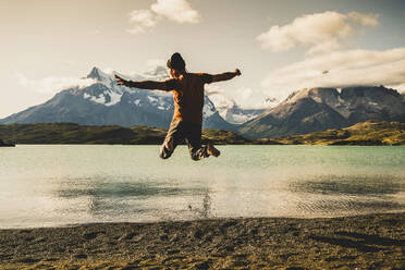 Man jumping and enjoying at lake Pehoe in Torres Del Paine National Park Patagonia, South America - UUF20846