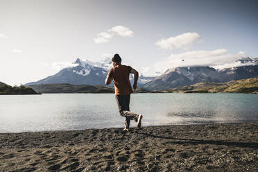 Mann läuft auf Sand am Pehoe-See im Torres Del Paine National Park Patagonien, Südamerika - UUF20848