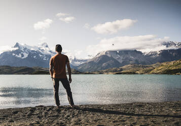Man standing and looking at view of Lake Pehoe in Torres Del Paine National Park Patagonia, South America - UUF20851