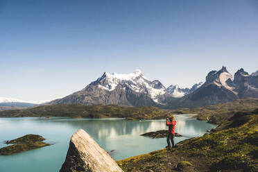 Man looking at Lake Pehoe through binocular in Torres Del Paine National Park, Chile Patagonia, South America - UUF20859