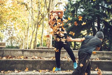 Junge Freunde spielen mit Herbstblättern im Park - EHF00733