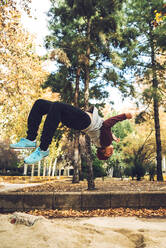 Young man jumping upside down in park during autumn - EHF00747