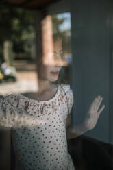 Girl looking away seen through glass window - GRCF00307