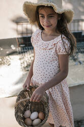 Girl holding wicker basket with freshly laid eggs - GRCF00310
