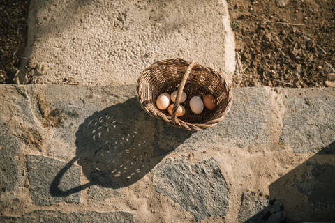 Eier im Weidenkorb auf Steinboden, lizenzfreies Stockfoto