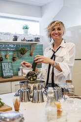 Smiling female chef using food processor in kitchen during cooking class - DLTSF01009