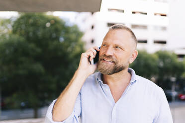 Close-up of smiling male entrepreneur talking on mobile phone - DGOF01195