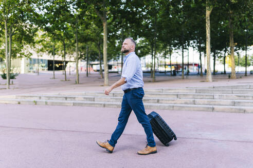 Geschäftsmann zu Fuß mit Koffer im Büropark - DGOF01221