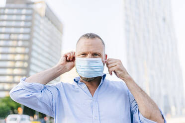 Businessman wearing face mask during coronavirus outbreak in city - DGOF01224