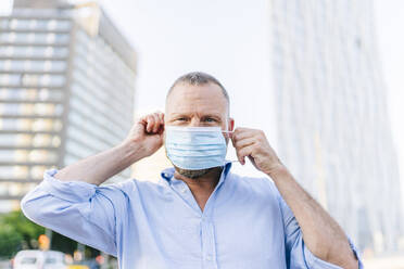 Geschäftsmann trägt Gesichtsmaske während des Ausbruchs des Coronavirus in der Stadt - DGOF01224