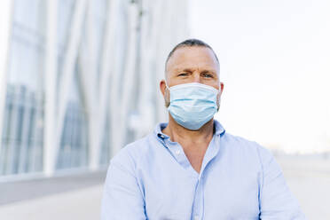 Mature businessman wearing protective face mask in city - DGOF01226