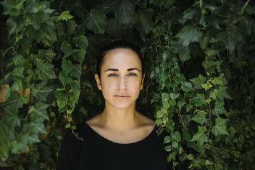 Close-up of serious mid adult woman against plants in park - XLGF00425