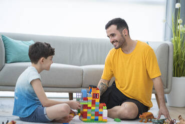 Lächelnder Vater spielt mit seinem Sohn im Wohnzimmer - SNF00474