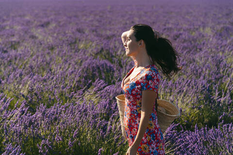 Portrait of beautiful woman standing in vast lavender field with hand in hair stock photo