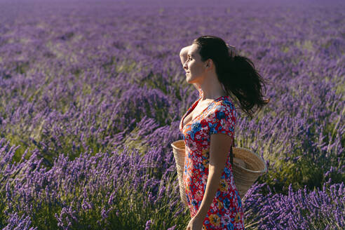 Porträt einer schönen Frau in einem weiten Lavendelfeld mit der Hand im Haar - GEMF03975