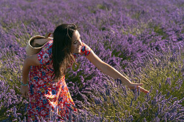 Schöne Frau berührt blühenden Lavendel auf einem Feld - GEMF03980