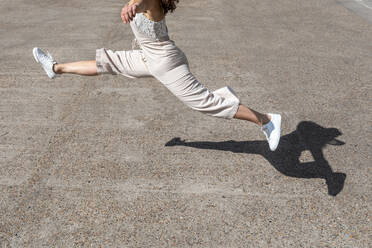 Beine einer jungen Frau, die an einem sonnigen Tag auf die Straße springt - WPEF03218