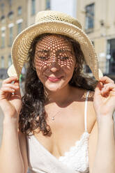 Nahaufnahme einer lächelnden schönen Frau mit geschlossenen Augen und Hut in der Stadt an einem sonnigen Tag - WPEF03220