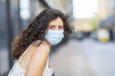 Close-up of young woman wearing mask in city - WPEF03222