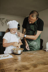 Father and daughter baking cookies at home - GMLF00424