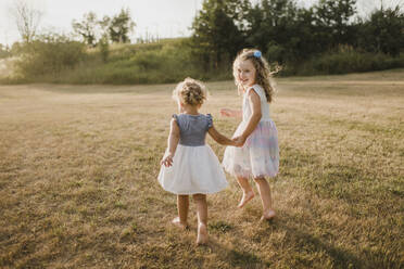 Girls walking hand in hand on a meadow - SMSF00088