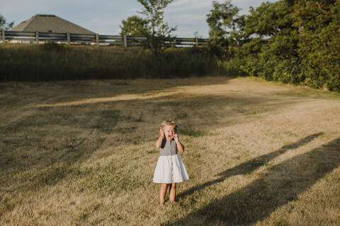 Weinendes kleines Mädchen, das allein auf einer Wiese steht, lizenzfreies Stockfoto