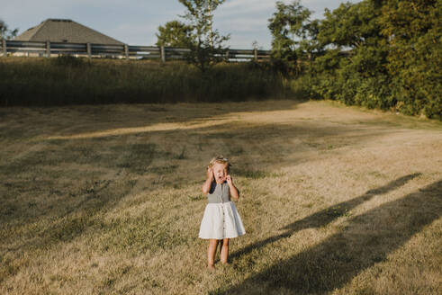 Crying little girl standing alone on a meadow - SMSF00092