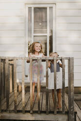 Two happy sisters standing on the porch at home - SMSF00103
