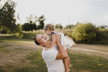 Happy father carrying little daughter on a meadow - SMSF00105