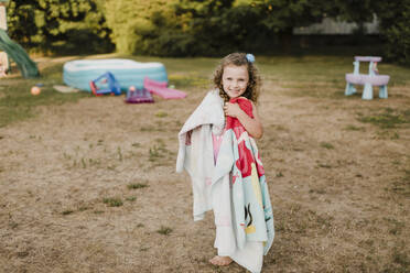 Porträt eines glücklichen Mädchens am aufblasbaren Schwimmbecken im Garten - SMSF00109