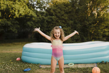 Porträt eines unbekümmerten Mädchens am aufblasbaren Swimmingpool im Garten - SMSF00112