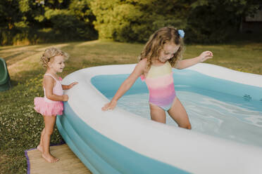 Two girls at inflatable swimming pool in garden - SMSF00115