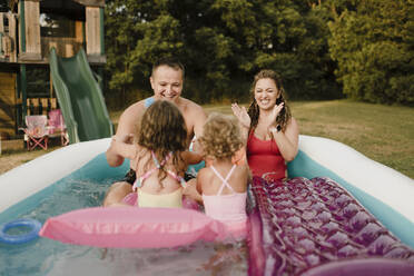 Glückliche Familie in einem aufblasbaren Schwimmbad im Garten - SMSF00118