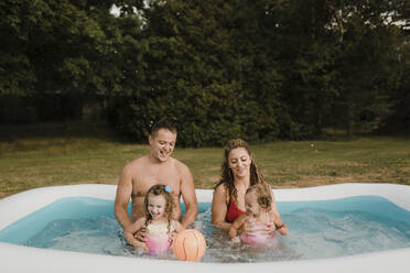 Glückliche Familie in einem aufblasbaren Schwimmbad im Garten - SMSF00120