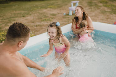 Glückliche Familie in einem aufblasbaren Schwimmbad im Garten - SMSF00124