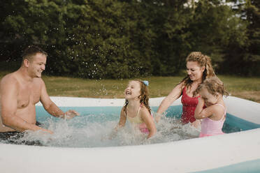 Glückliche Familie in einem aufblasbaren Schwimmbad im Garten - SMSF00125