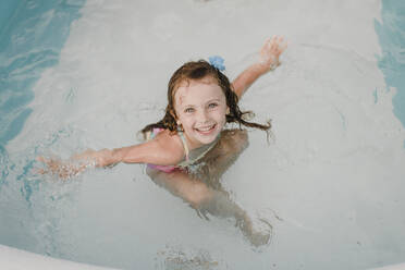 Porträt eines glücklichen Mädchens in einem aufblasbaren Schwimmbecken - SMSF00127