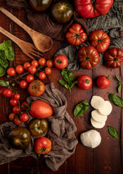 Frische Tomaten und Mozzarellakäse mit Basilikumblättern für Salat auf Holzbrett und Stoffserviette - ADSF09501